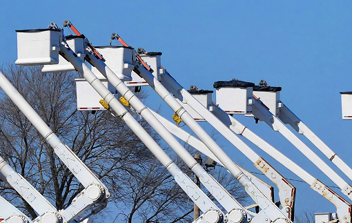 Several bucket trucks with their bucket arms extended and raised high in the air.