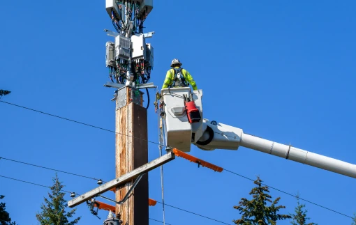 Two workers in buckets, elevated to work on electrical wires.