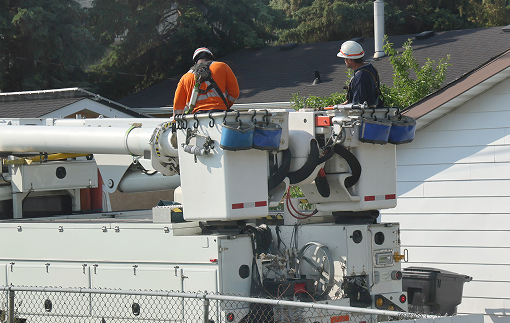Two workers in buckets, elevated to work on electrical wires.